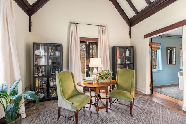 living area featuring beamed ceiling, high vaulted ceiling, and a healthy amount of sunlight