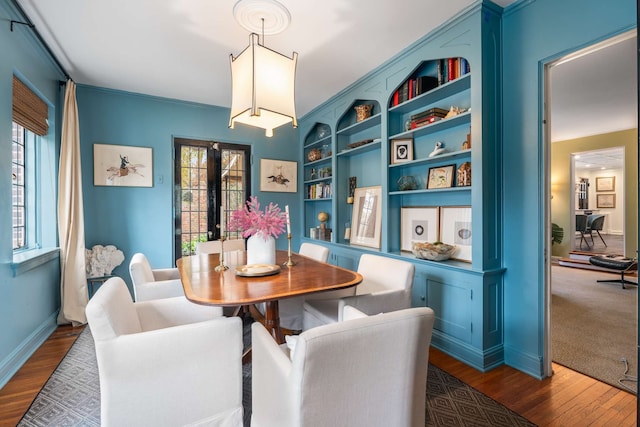 dining space with built in shelves, french doors, dark wood-type flooring, and ornamental molding