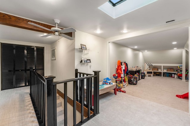 recreation room featuring carpet, ceiling fan, and vaulted ceiling with skylight