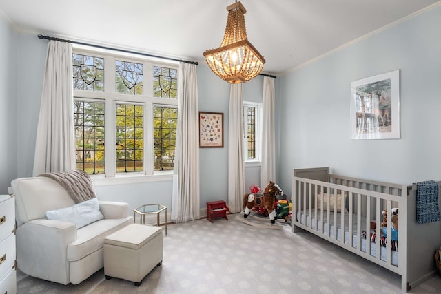 bedroom with light carpet, a nursery area, a notable chandelier, and ornamental molding