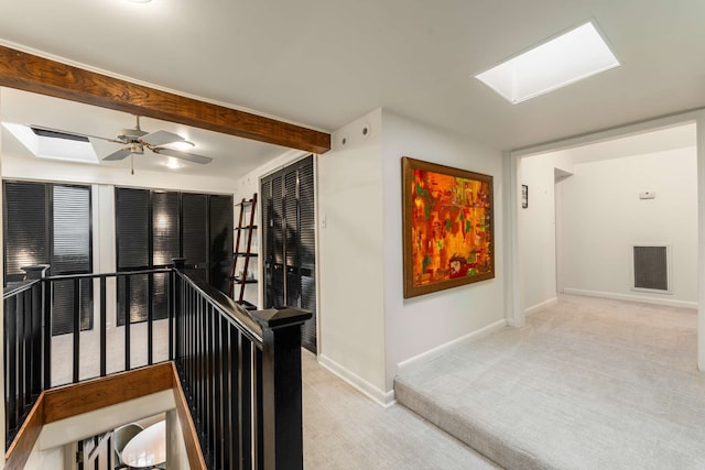 hallway with light colored carpet and a skylight