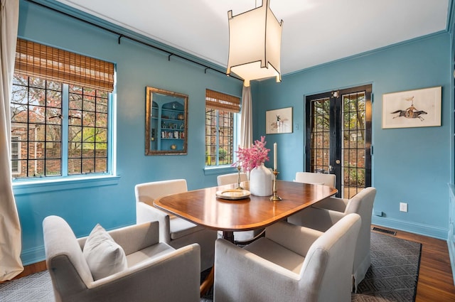 dining area with french doors, a wealth of natural light, and dark wood-type flooring