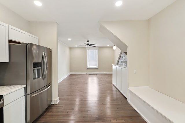 kitchen with stainless steel fridge, dark hardwood / wood-style flooring, light stone counters, ceiling fan, and white cabinetry