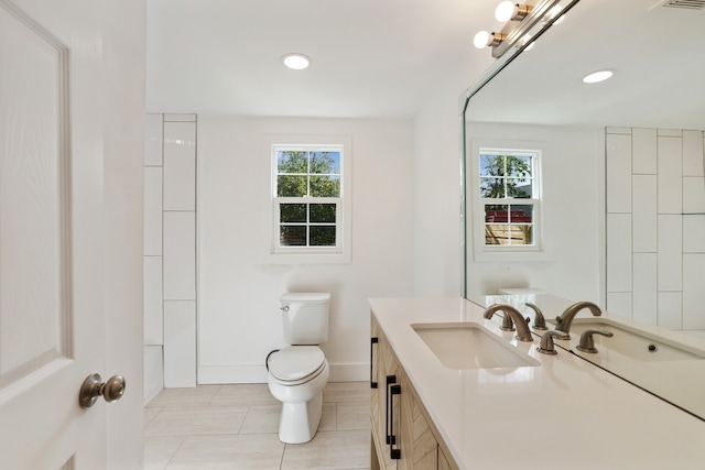 bathroom with tile patterned floors, a wealth of natural light, vanity, and toilet