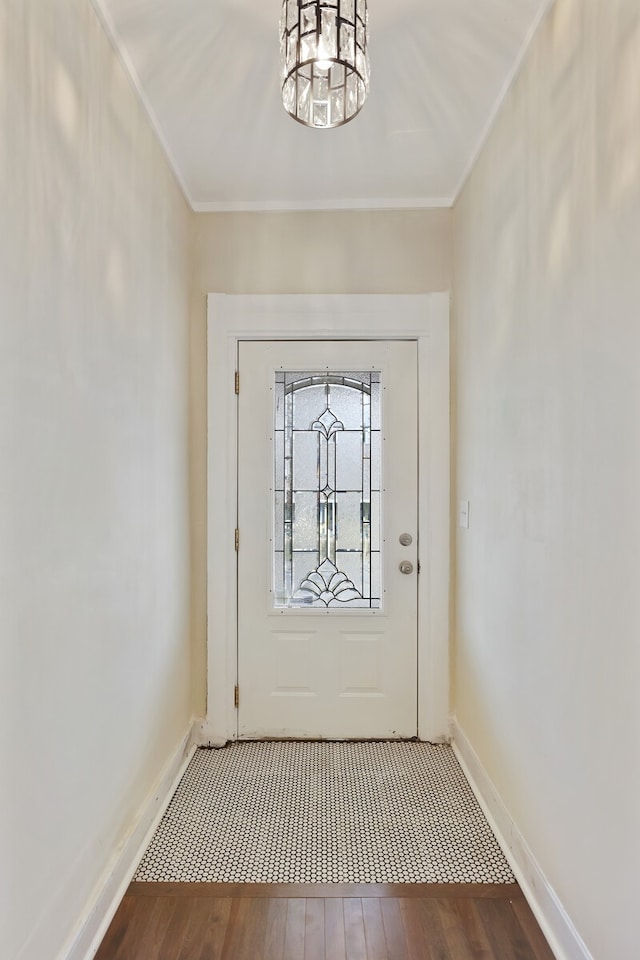 entryway featuring wood-type flooring, crown molding, and an inviting chandelier