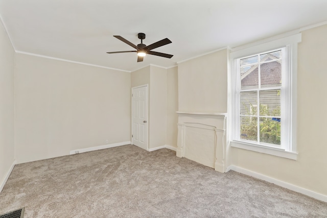 carpeted empty room with a wealth of natural light, crown molding, and ceiling fan