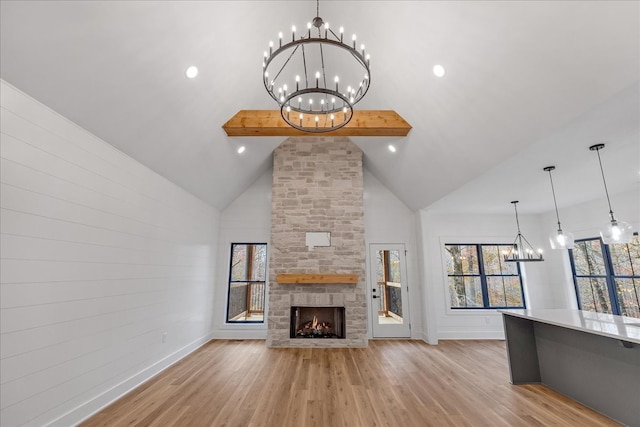 unfurnished living room with a fireplace, light hardwood / wood-style flooring, high vaulted ceiling, and a chandelier