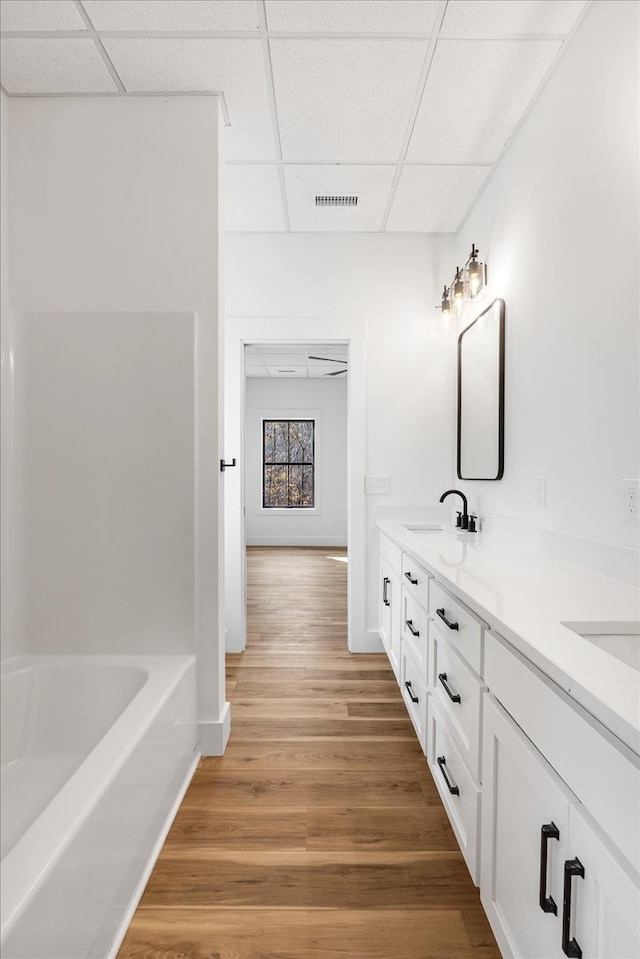 bathroom featuring hardwood / wood-style flooring, a drop ceiling, and vanity