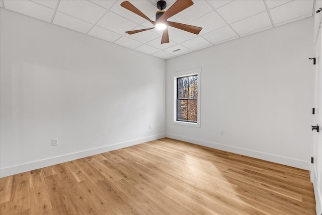 empty room with a paneled ceiling, ceiling fan, and light hardwood / wood-style floors