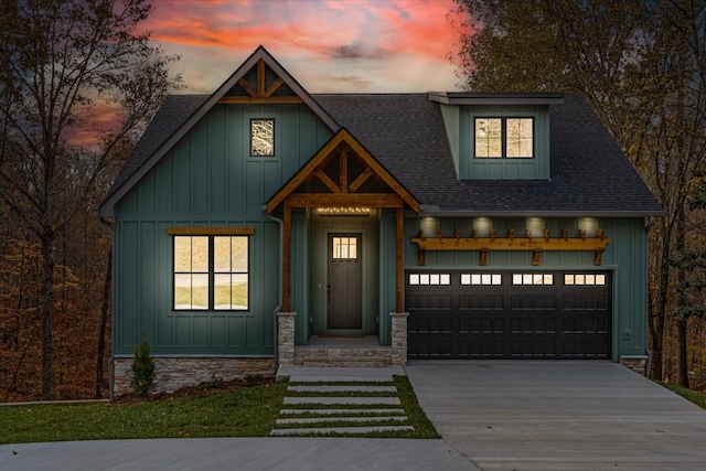 view of front of home with board and batten siding, a shingled roof, concrete driveway, a garage, and stone siding