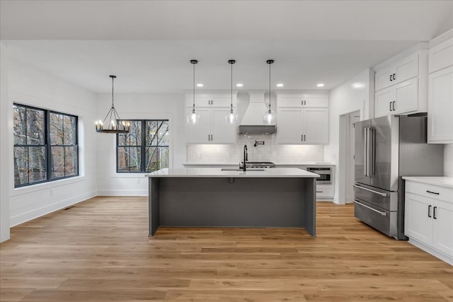 kitchen featuring white cabinets, appliances with stainless steel finishes, light hardwood / wood-style flooring, and hanging light fixtures