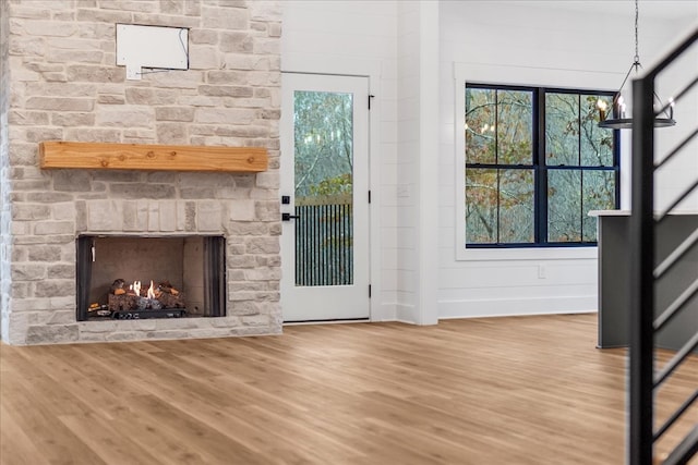 unfurnished living room featuring hardwood / wood-style floors and a stone fireplace