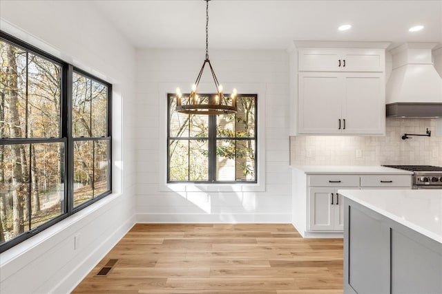 unfurnished dining area featuring a chandelier, light hardwood / wood-style floors, and wood walls