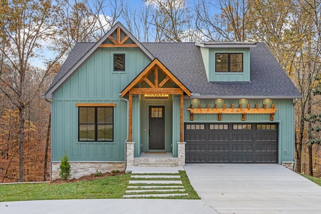 view of front of home featuring a garage, board and batten siding, driveway, and roof with shingles