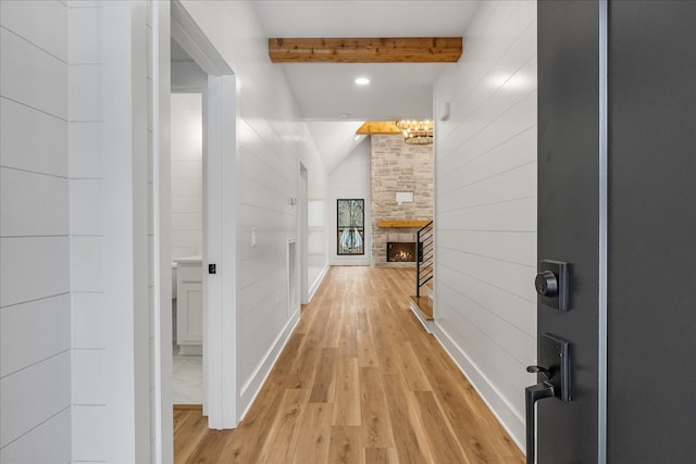 corridor with light wood-type flooring and lofted ceiling with beams