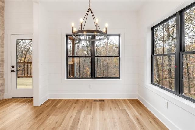 unfurnished dining area with light hardwood / wood-style floors and a notable chandelier