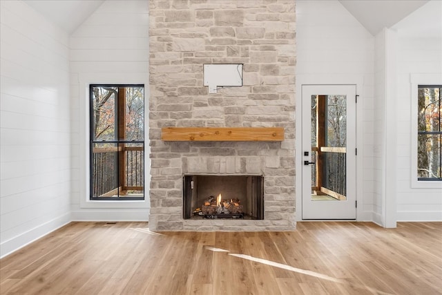 unfurnished living room featuring a stone fireplace, plenty of natural light, and hardwood / wood-style flooring