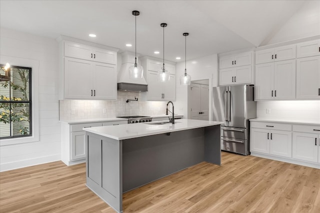 kitchen featuring white cabinetry, sink, high end refrigerator, pendant lighting, and light hardwood / wood-style floors