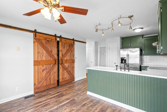 kitchen with stainless steel refrigerator with ice dispenser, a barn door, dark wood-type flooring, and green cabinets