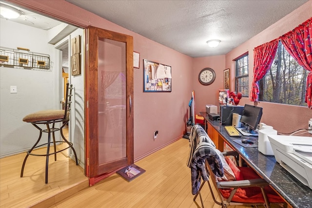 home office with a textured ceiling and light wood-type flooring