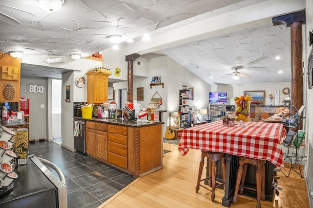 kitchen with dishwasher, dark hardwood / wood-style floors, ceiling fan, kitchen peninsula, and decorative columns