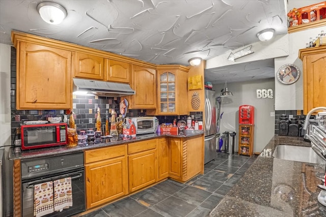 kitchen with sink, stainless steel appliances, dark stone counters, and tasteful backsplash