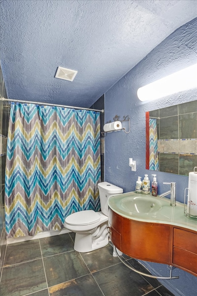 bathroom featuring tile patterned flooring, a textured ceiling, vanity, and toilet