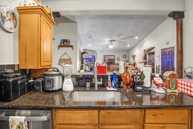 kitchen with ceiling fan, dishwasher, sink, backsplash, and dark stone counters