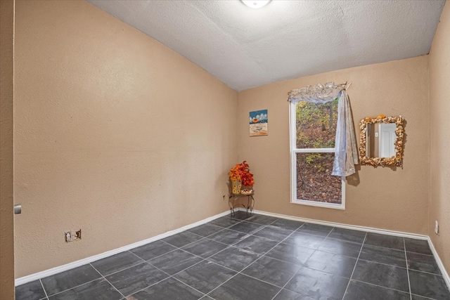 tiled spare room with vaulted ceiling and a textured ceiling