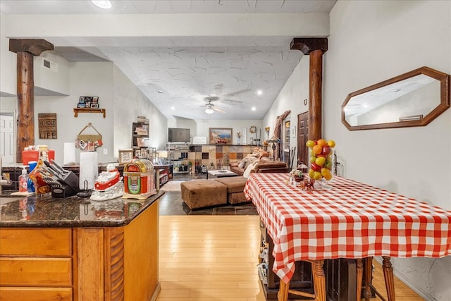 dining area with light hardwood / wood-style floors, ceiling fan, lofted ceiling, and decorative columns