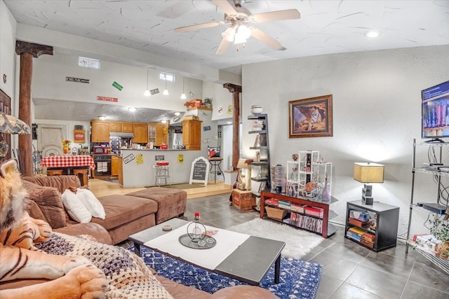 tiled living room featuring ceiling fan and ornate columns