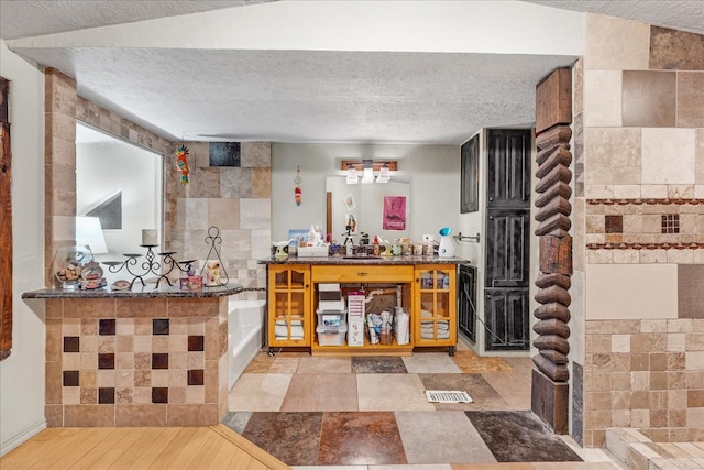 bar with sink, wine cooler, a textured ceiling, tile walls, and light wood-type flooring