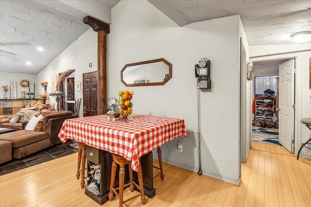 dining room with ornate columns, wood-type flooring, and lofted ceiling