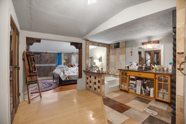 bathroom with hardwood / wood-style flooring, vanity, a tub, and a textured ceiling