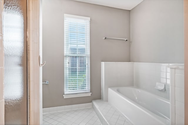 bathroom with tile patterned flooring and a tub to relax in