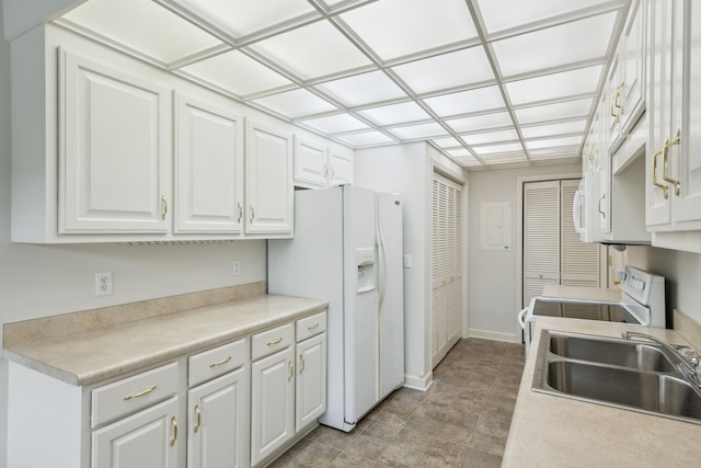 kitchen with white cabinets, white fridge with ice dispenser, range, and sink