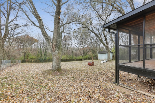 view of yard featuring a sunroom and a storage unit