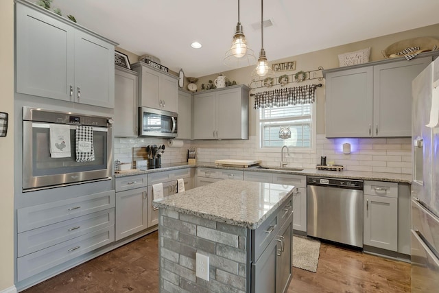 kitchen featuring light stone countertops, sink, a center island, dark hardwood / wood-style flooring, and appliances with stainless steel finishes