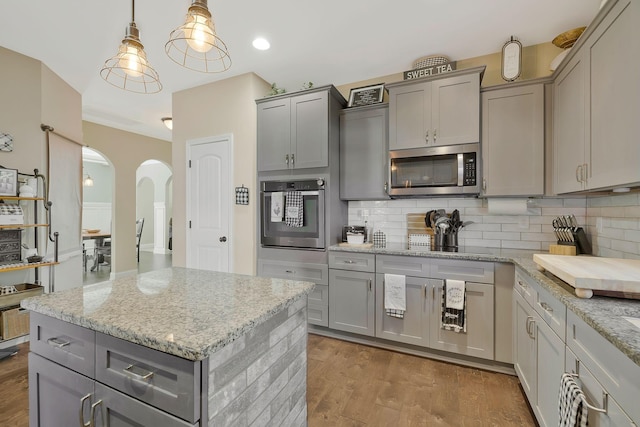 kitchen with hardwood / wood-style floors, decorative light fixtures, gray cabinetry, and appliances with stainless steel finishes