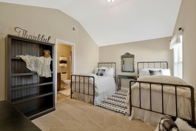 bedroom featuring ensuite bathroom, light colored carpet, and lofted ceiling