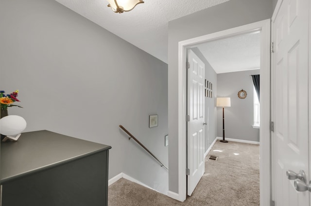 staircase featuring lofted ceiling, carpet floors, and a textured ceiling