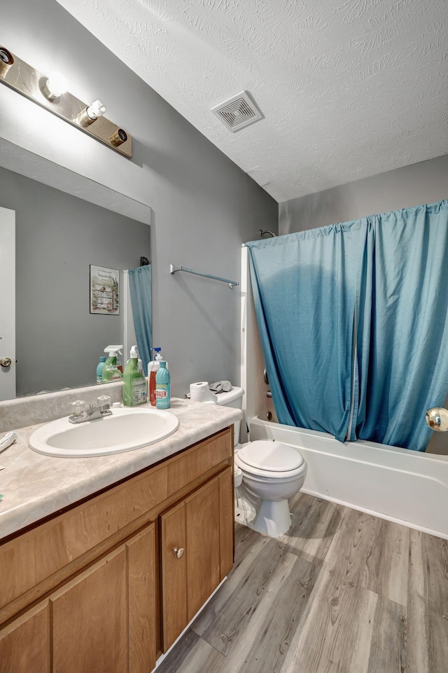 full bathroom featuring hardwood / wood-style floors, vanity, a textured ceiling, and shower / tub combo with curtain