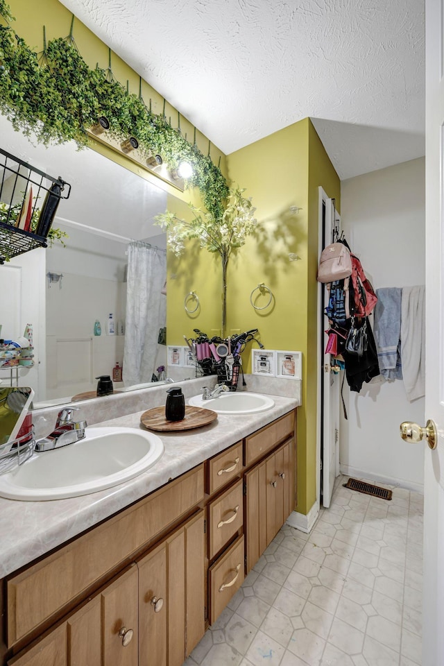 bathroom with vanity, a textured ceiling, and walk in shower