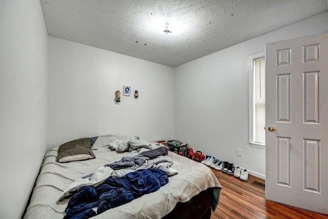 bedroom featuring hardwood / wood-style floors and a textured ceiling