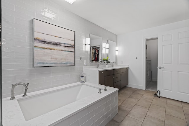 bathroom with tiled bath, tile patterned flooring, and vanity