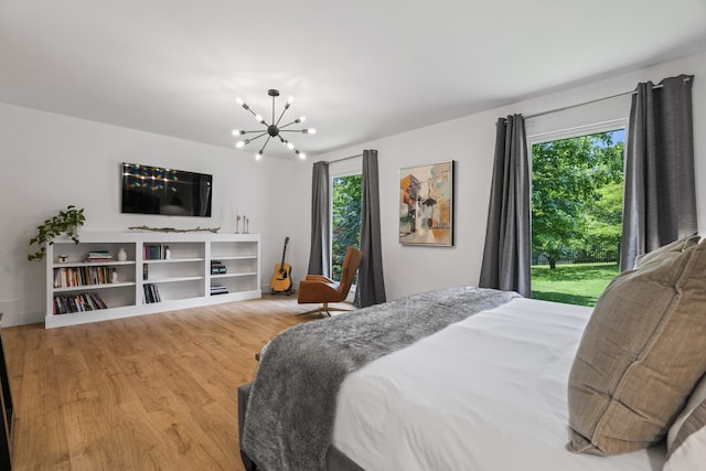 bedroom with multiple windows, hardwood / wood-style floors, and a notable chandelier