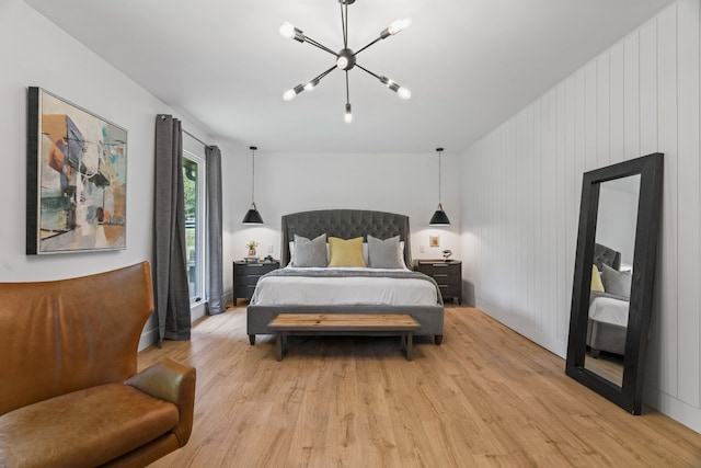 bedroom with wooden walls, light hardwood / wood-style floors, and a notable chandelier