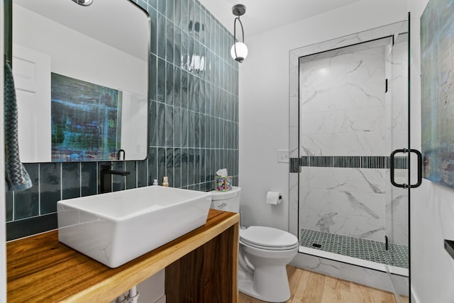 bathroom featuring hardwood / wood-style floors, vanity, toilet, tile walls, and an enclosed shower