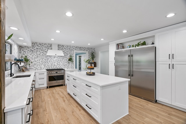 kitchen featuring white cabinets, sink, premium appliances, a kitchen island, and custom range hood