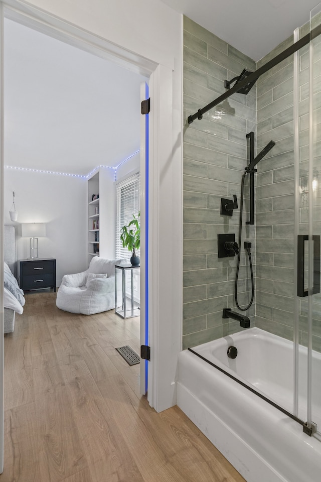 bathroom with hardwood / wood-style floors and enclosed tub / shower combo